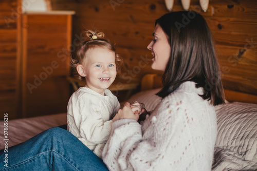 Young mother and her daughter playing and having fun in a cozy log cabin.