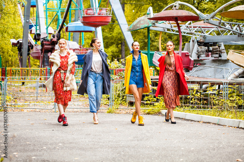 Four fashion models walking in autumn park