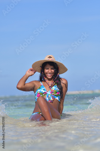 African American Woman siting on beach inside blue water splash. Natural laughing , Caribbean Beach Background