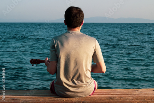 A boy playing ukulele on the beach