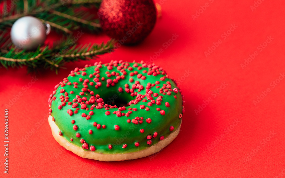 christmas composition of green donut, new year balls and tree branches on a red background. Celebration, food art, holiday concept. side view. copy space. christmas composition of green donut, new year balls and tree branches on a red background. Celebration, food art, holiday concept. side view. copy space.