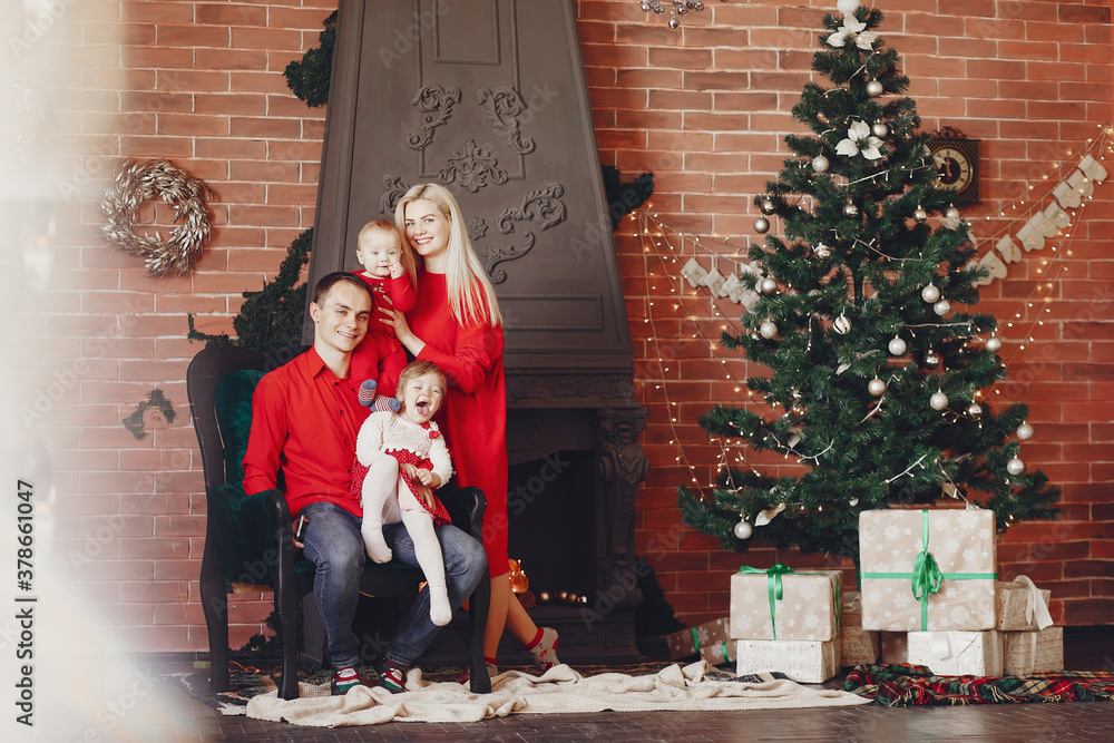 Beautiful mother in a red dress. Family sitting near christmas gifts. Little girl and boy near christmas tree Beautiful mother in a red dress. Family sitting near christmas gifts. Little girl and boy near christmas tree