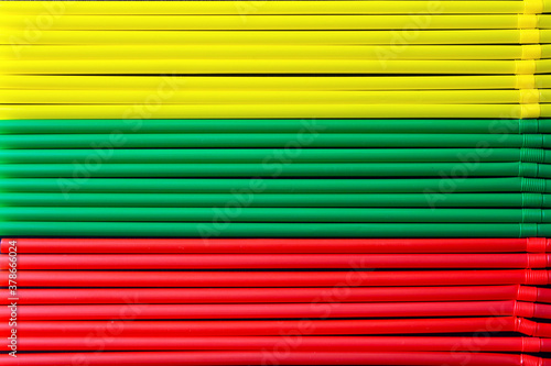 top view of yellow, green and red plastic drinking straws in a row. Colours of flag of Lithuania. 
