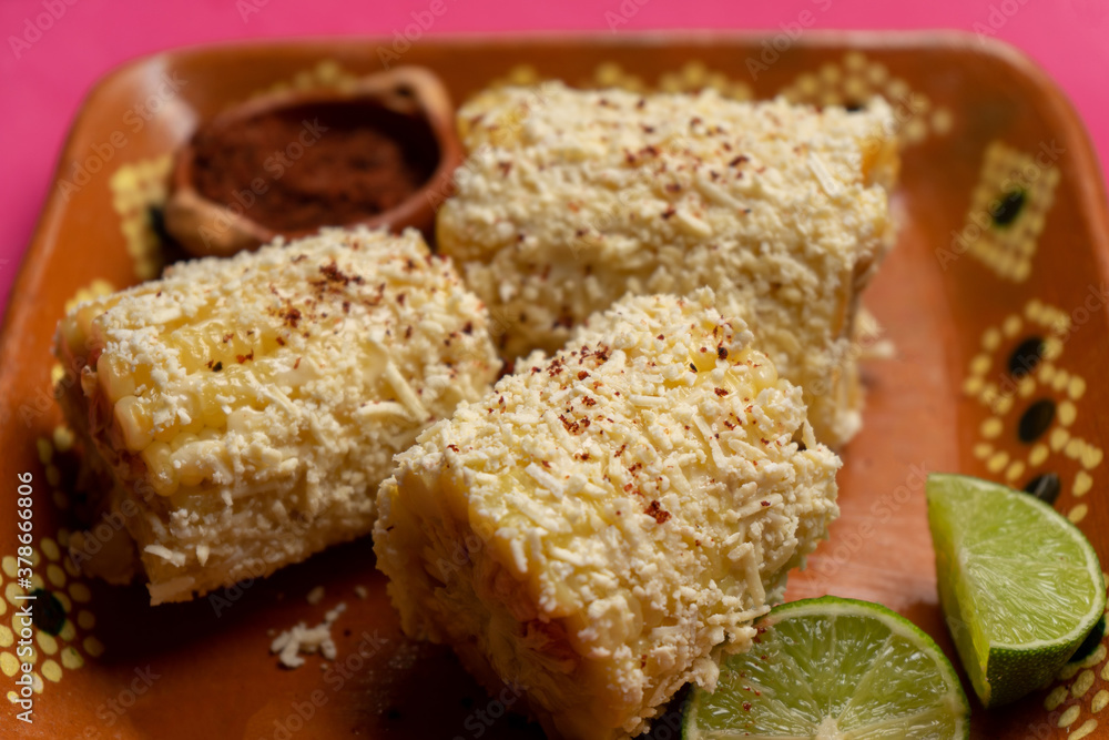 Mexican corn on the cob also called elotes with cheese and mayonnaise on pink background Mexican corn on the cob also called elotes with cheese and mayonnaise on pink background
