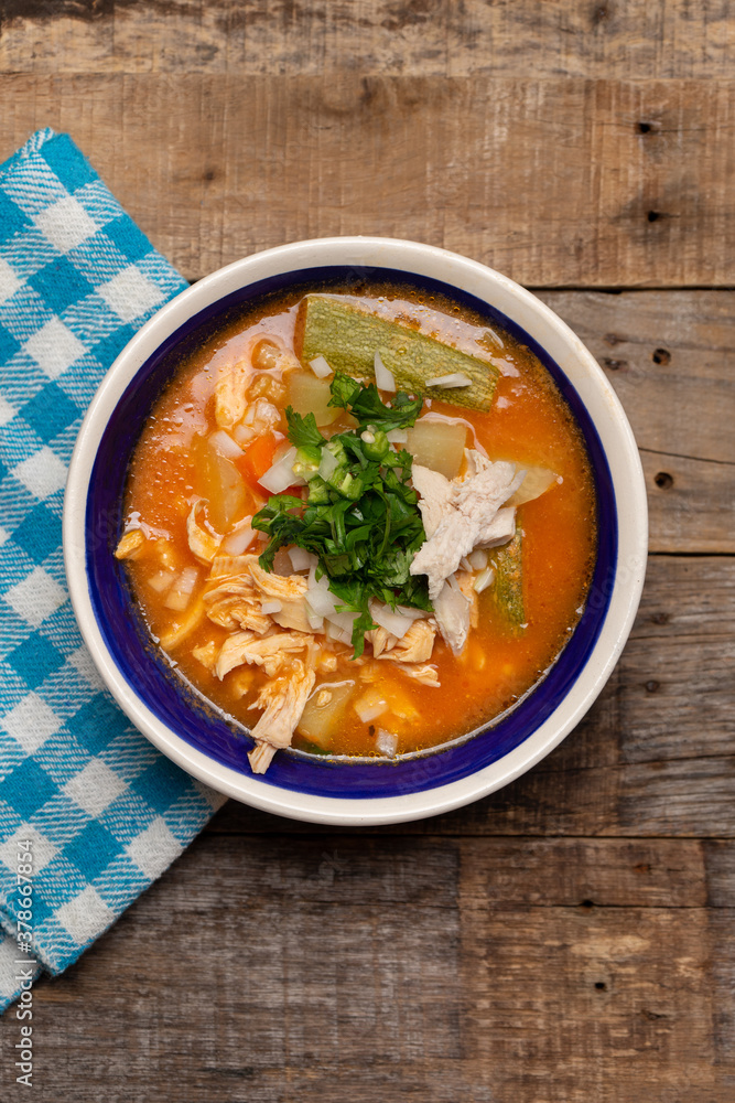Mexican chicken soup with vegetables and rice on wooden background Mexican chicken soup with vegetables and rice on wooden background