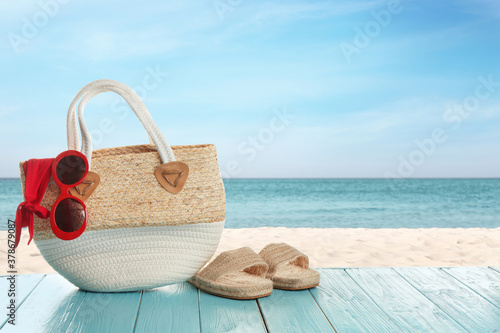 Beach accessories on turquoise wooden surface near ocean, space for text