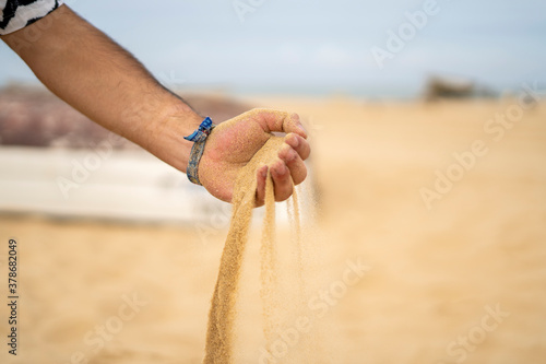 Mano dejando caer arena en la playa  photo