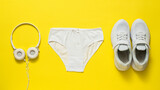 White panties, sneakers and headphones on a yellow background.