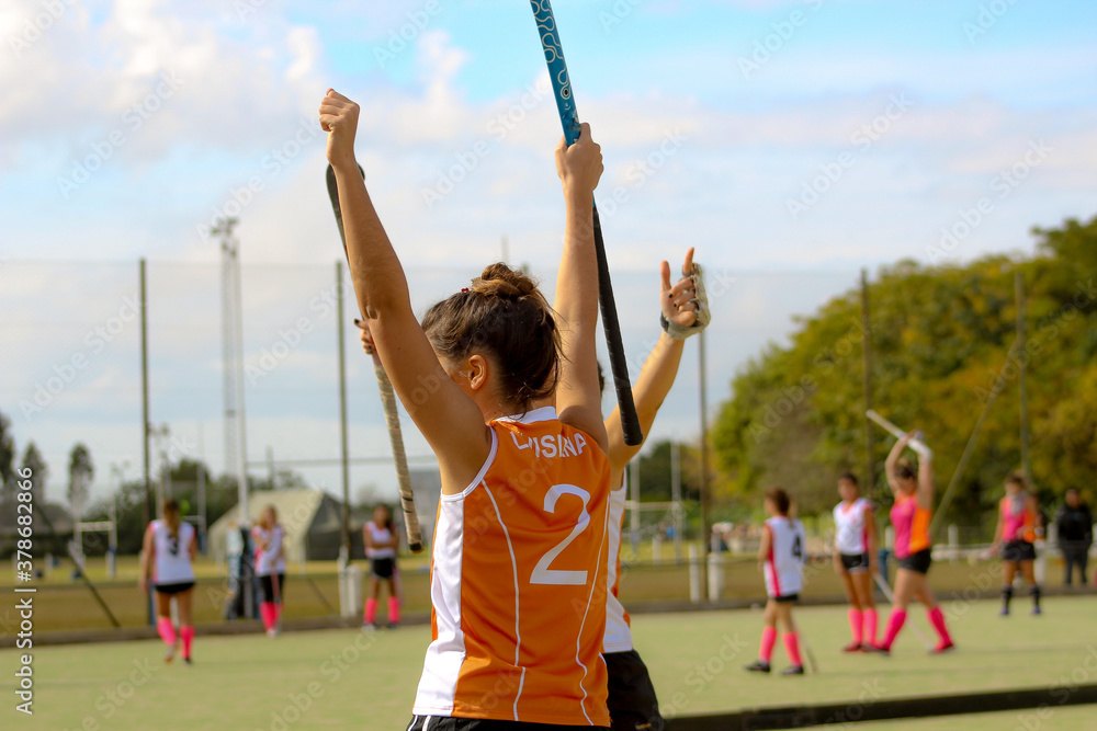 Field hockey female player celebrating during a match outdoors with hockey stick