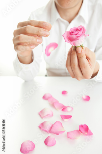 man pulling petals from rose