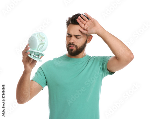 Man with portable fan suffering from heat on white background. Summer season