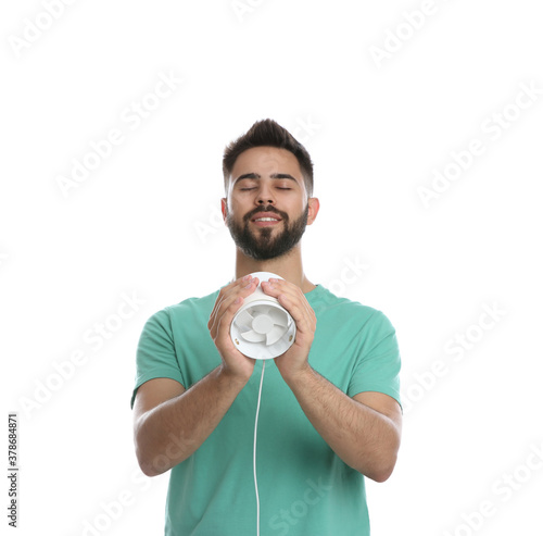 Man enjoying air flow from portable fan on white background. Summer heat