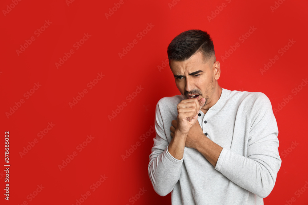 Man coughing on red background, space for text. Cold symptoms Man coughing on red background, space for text. Cold symptoms