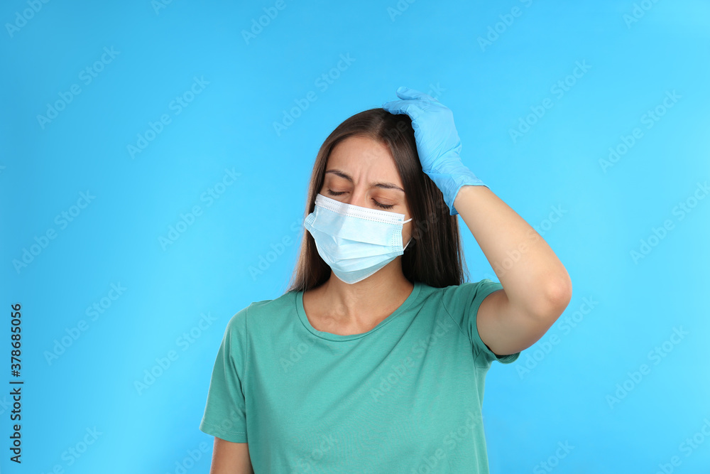 Stressed woman in protective mask on light blue background. Mental health problems during COVID-19 pandemic Stressed woman in protective mask on light blue background. Mental health problems during COVID-19 pandemic