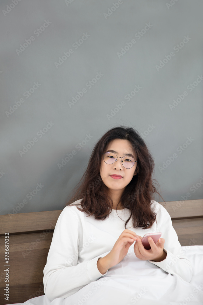 Beautiful morning girl sitting on bed and playing with mobile phone Beautiful morning girl sitting on bed and playing with mobile phone