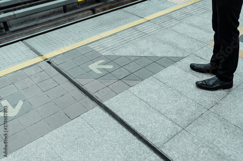 Man waiting for train on platform at arrow line on the floor.