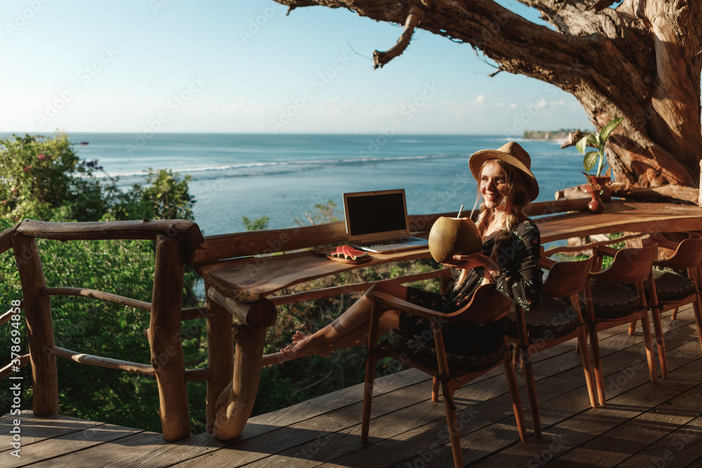 custom made wallpaper toronto digitalTechnology and travel. Working outdoors. Pretty young woman using laptop in cafe on tropical beach cafe with sea view, drink coconut juice