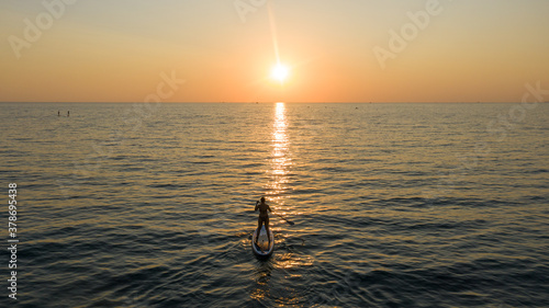 Paddle boarder. Black sunset silhouette of young man on stand up paddleboard. Water sport activity, SUP surfing. silhouette paddleboarding at sunset, recreation sport paddling ocean beach surf orange