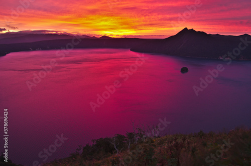 夜明けの湖の燃えるような朝焼けの空。摩周湖、北海道。 © Masa Tsuchiya