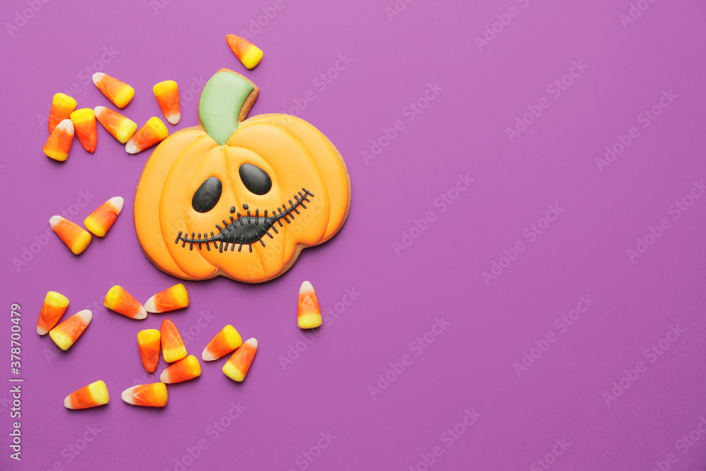Tasty candies and cookie for Halloween on color background