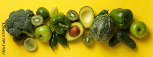 Green vegetables and fruits on yellow background