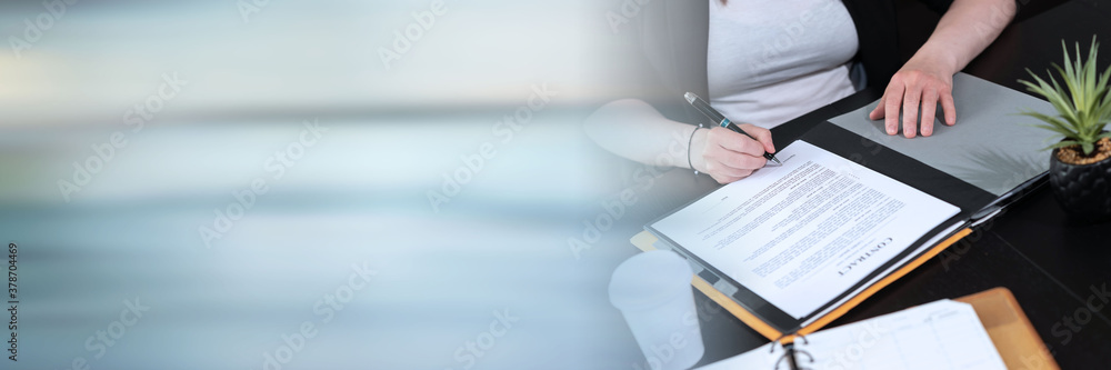 Businesswoman signing a document; panoramic banner Businesswoman signing a document; panoramic banner