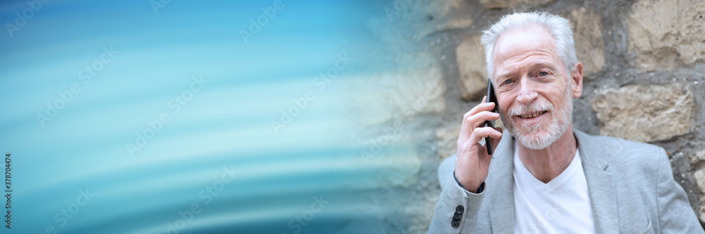 Mature man using his mobile phone; panoramic banner Mature man using his mobile phone; panoramic banner