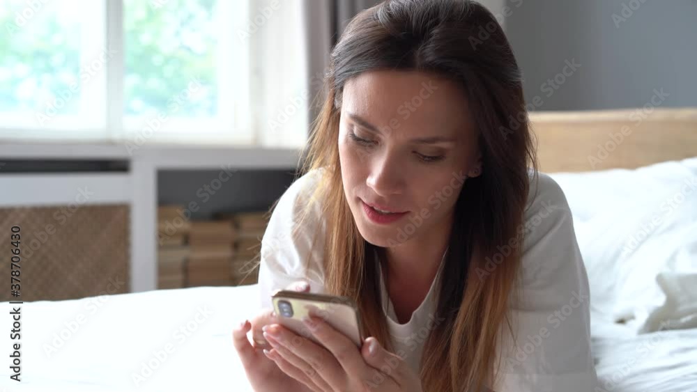 Stay at home. Beautiful woman lies on the bed and use smartphone Stay at home. Beautiful woman lies on the bed and use smartphone