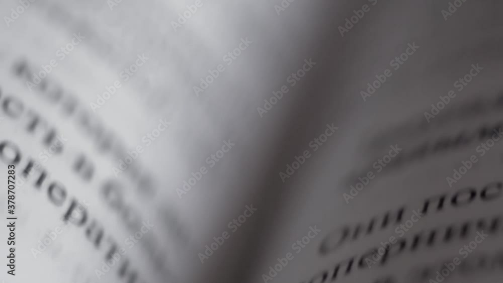 Printed lines of text consisting of words with black letters on pages of hardcover book made of white paper on fold of textbook fast movement of camera from top to bottom with variable focus close up Printed lines of text consisting of words with black letters on pages of hardcover book made of white paper on fold of textbook fast movement of camera from top to bottom with variable focus close up