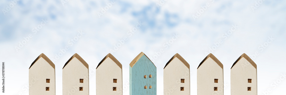 row of miniature wood houses, blue house among white houses with sky background, hunting and searching concept for real estate industry