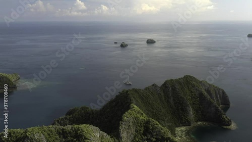 Raja Ampat, Misool. High-flying aerial shot over jagged clipped islands with schnooer style ship in the background.