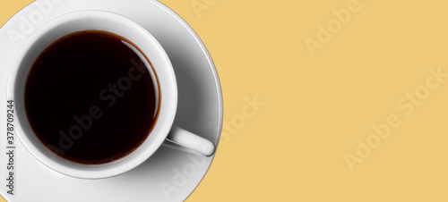 White cup of coffee on dijon honey background. Top view. Copy space. 