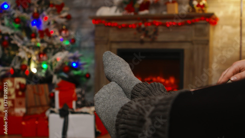 Close up of woman feet relaxing on boyfriend knees on christmas day sitting on couch. Christmas couple magic cozy warm fireplace, spending festive holidays together in family © DC Studio