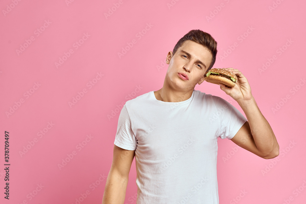 man with big hamburger on pink background calories fast food cropped view Copy Space close-up man with big hamburger on pink background calories fast food cropped view Copy Space close-up