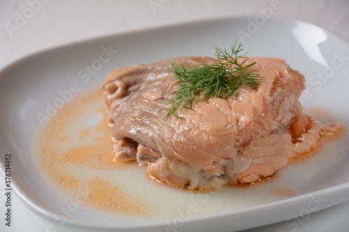 Canned salmon chunks with lettuce leaves,on white plate
