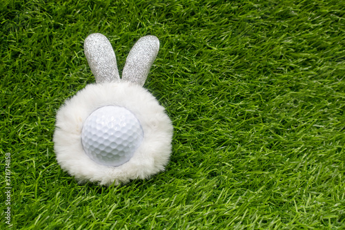 Golf ball for Easter Holiday with bunny hat on green grass background