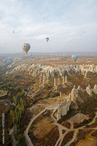 Colorful hot air balloon ride and tour in Goreme valley, semi-arid region in central Turkey known for its distinctive fairy chimneys, tall, cone-shaped rock formation- Cappadocia, Turkey