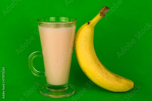  Juice, nectar from a banana in a glass on a bright green background.