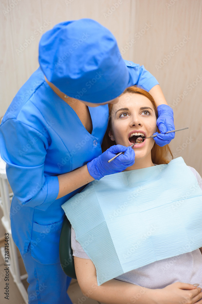 Doctor in uniform checking up female patient's teeth in dental clinic. Doctor in uniform checking up female patient's teeth in dental clinic.