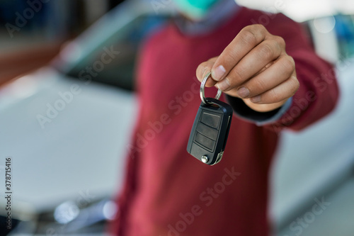 Close-up of a man holding car keys in a workshop.