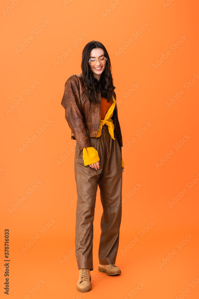 full length of young woman in autumn outfit and glasses standing on orange full length of young woman in autumn outfit and glasses standing on orange