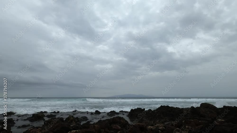 Time Lapse Fast movement view of winter beach with cloudy sky and bad weather - surf people in the waves - action extreme concept tourism and outdoor leisure activity Time Lapse Fast movement view of winter beach with cloudy sky and bad weather - surf people in the waves - action extreme concept tourism and outdoor leisure activity