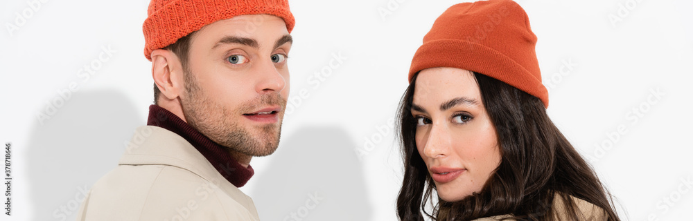panoramic concept of trendy couple in beanie hats looking at camera on white panoramic concept of trendy couple in beanie hats looking at camera on white