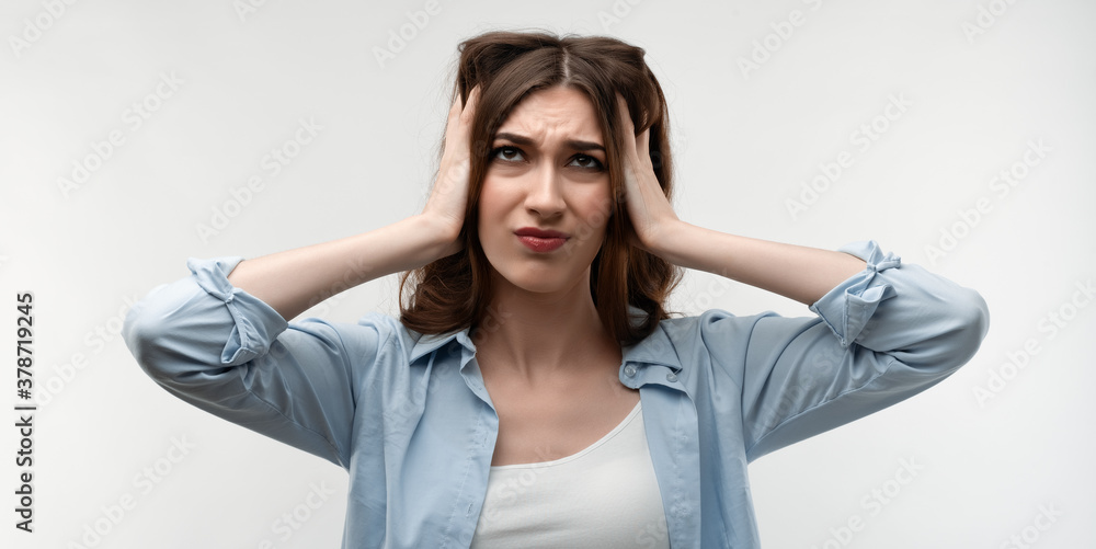 Naklejka premium Image of stressed woman with long chestnut hair grabbing her head. Emotional helplessness. Studio shot, white background