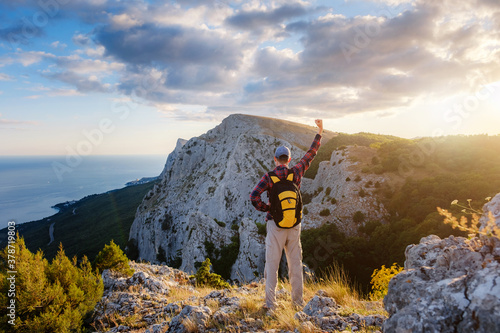 Adventurous man is on top of the mountain and enjoying the beautiful view during a vibrant sunset