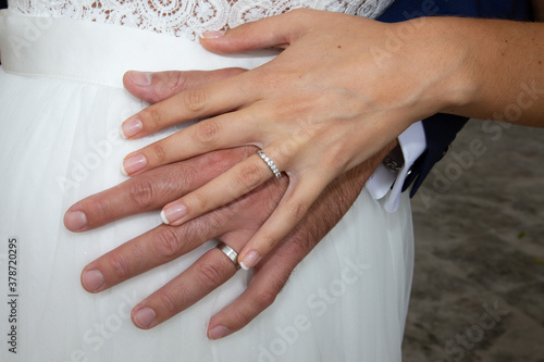 wedding rings on bride and groom hands on marriage white dress background