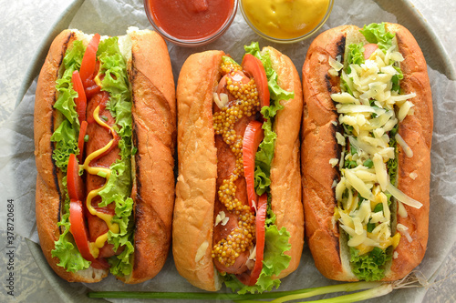 Hot dogs with various fillings. Dark background. food background with copy space. Top view. Hot dogs with mustard and ketchup, lettuce, cheese and tomatoes. Closeup