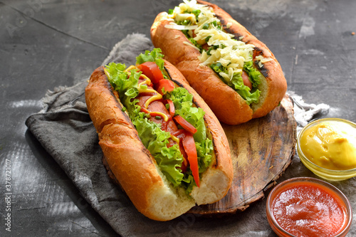 Hot dogs with various fillings. Dark background. food background with copy space. Hot dogs with mustard and ketchup, lettuce, cheese and tomatoes. Close up