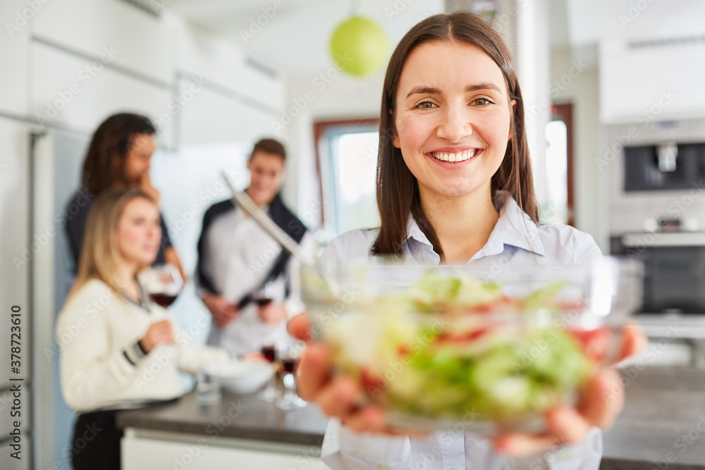 Junge lächelnde Frau in Küche mit einer Schüssel Salat