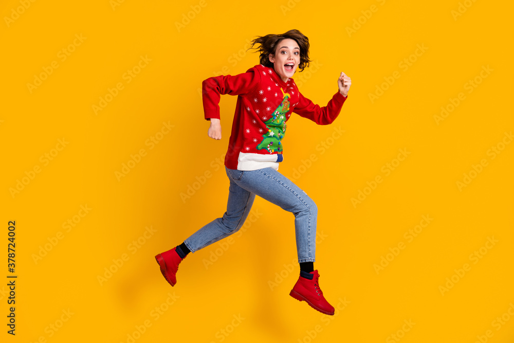 Full length profile side photo of excited girl jump run hurry x-mas tradition discounts wear christmas tree sweater pullover denim jeans isolated bright shine color background